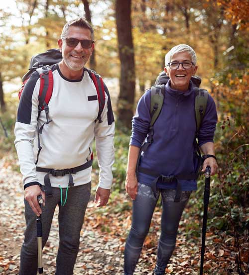 Happy, retired couple hiking in the woods during fall season.